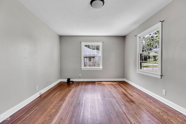2719 Stratford Dr, Greensboro, NC 27408 - unfurnished room with healthy amount of natural light, hardwood / wood-style floors, a textured ceiling, and baseboards