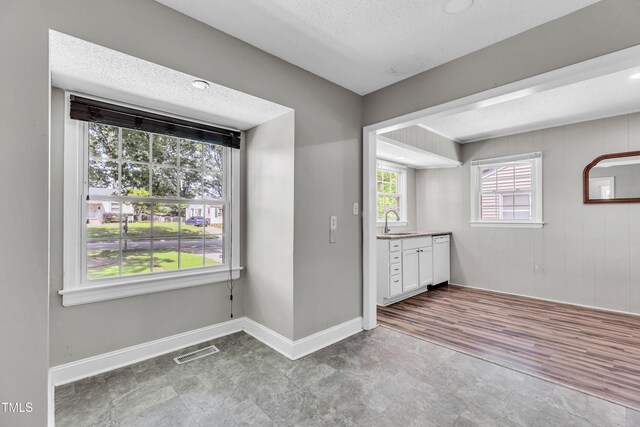 2719 Stratford Dr, Greensboro, NC 27408 - unfurnished dining area featuring a sink, baseboards, and a textured ceiling