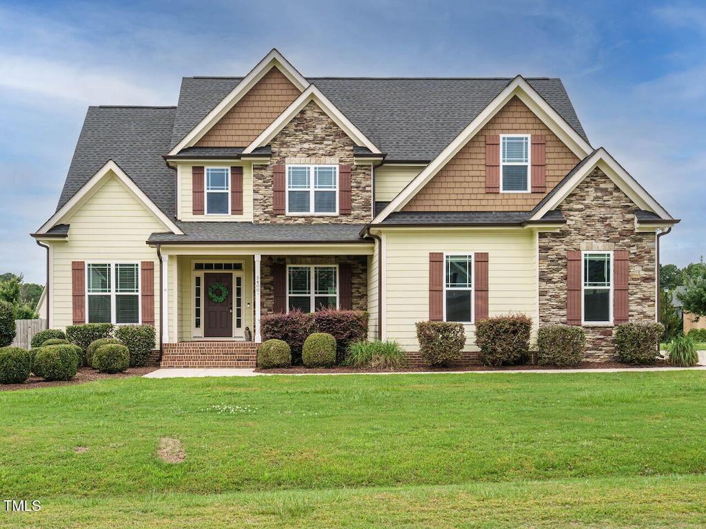 5400 Falconton Ln, Raleigh, NC 27610 - craftsman-style house featuring stone siding, a front yard, and roof with shingles