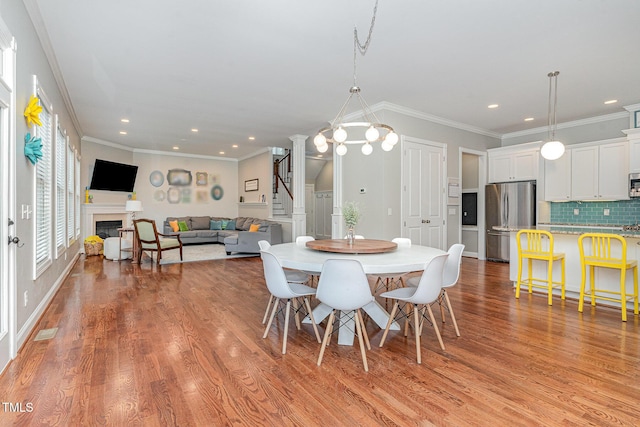 1138 Bexley Hills Bnd, Apex, NC 27502 - dining area with ornamental molding, light wood-style flooring, recessed lighting, stairs, and a fireplace