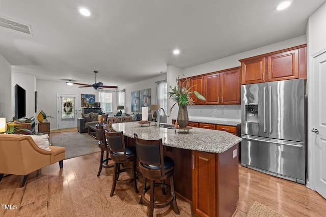 8132 Wheeler Woods Dr, Apex, NC 27539 - kitchen with stainless steel fridge with ice dispenser, light wood finished floors, open floor plan, light stone counters, and recessed lighting