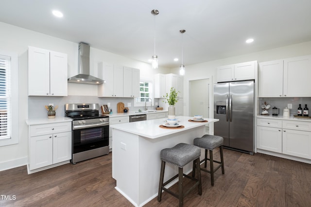 1318 N Alston Ave, Durham, NC 27701 - kitchen featuring appliances with stainless steel finishes, wall chimney range hood, a breakfast bar area, dark wood-style floors, and recessed lighting