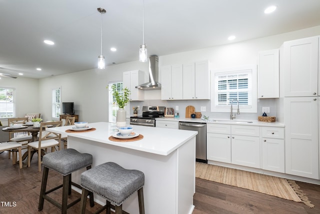 1318 N Alston Ave, Durham, NC 27701 - kitchen with wall chimney range hood, appliances with stainless steel finishes, a sink, a kitchen breakfast bar, and a center island