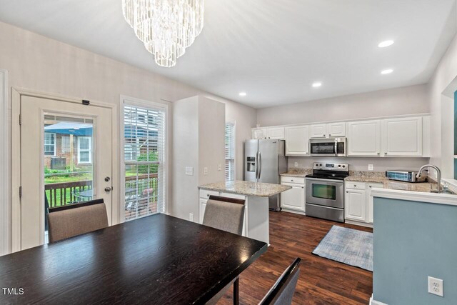 5505 Heather Garden Way, Raleigh, NC 27613 - kitchen with appliances with stainless steel finishes, a chandelier, dark wood-type flooring, white cabinetry, and recessed lighting