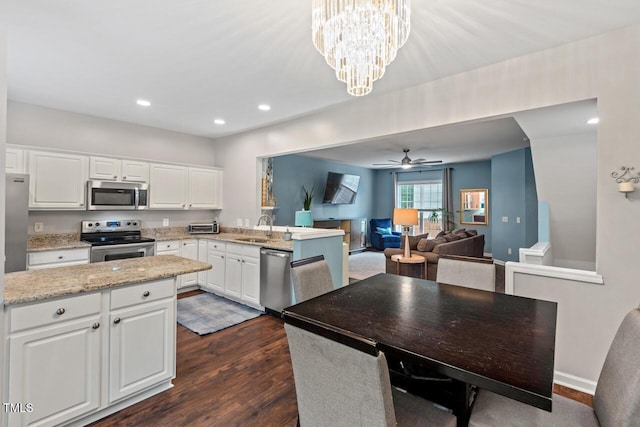 5505 Heather Garden Way, Raleigh, NC 27613 - kitchen with appliances with stainless steel finishes, dark wood-style flooring, a peninsula, white cabinetry, and light stone countertops