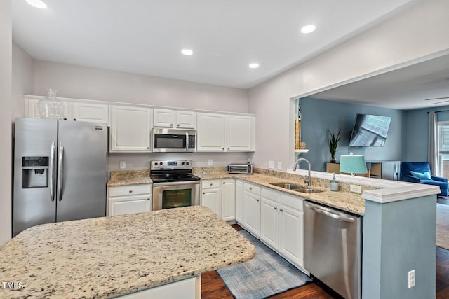 5505 Heather Garden Way, Raleigh, NC 27613 - kitchen with appliances with stainless steel finishes, dark wood-type flooring, white cabinetry, open floor plan, and a peninsula