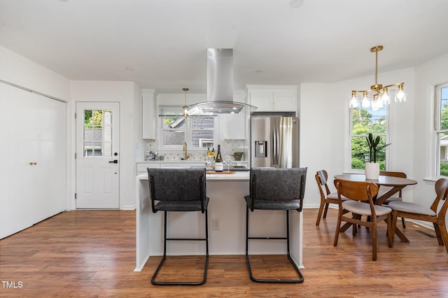 828 Cotton Pl, Raleigh, NC 27601 - kitchen featuring island exhaust hood, stainless steel refrigerator with ice dispenser, light countertops, white cabinetry, and wood finished floors
