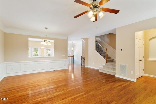 2614 Laurelcherry St, Raleigh, NC 27612 - unfurnished living room with wood finished floors, ceiling fan, a chandelier, ornamental molding, and stairs