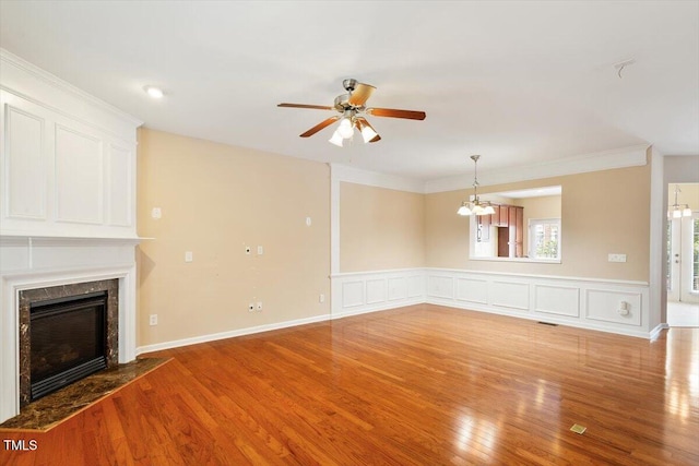 2614 Laurelcherry St, Raleigh, NC 27612 - unfurnished living room with a chandelier, a ceiling fan, a premium fireplace, light wood finished floors, and a wainscoted wall