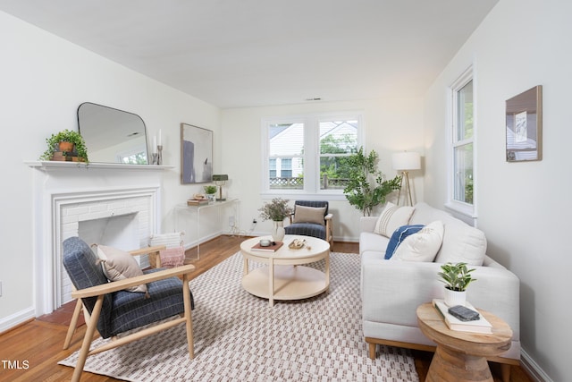 2523 Glendale Ave, Durham, NC 27704 - living room featuring wood finished floors, a brick fireplace, and baseboards