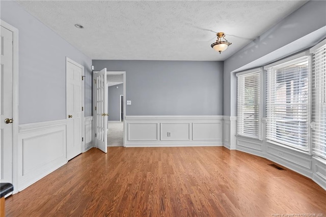 1608 Piney Creek Pl, Fayetteville, NC 28304 - spare room featuring wood finished floors, a textured ceiling, and a wainscoted wall