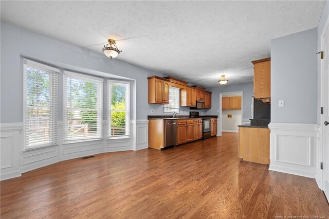 1608 Piney Creek Pl, Fayetteville, NC 28304 - kitchen with stainless steel appliances, dark countertops, wainscoting, dark wood-style flooring, and a textured ceiling