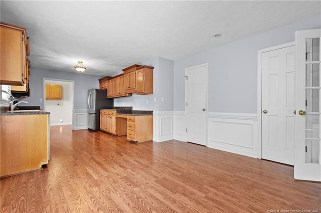 1608 Piney Creek Pl, Fayetteville, NC 28304 - kitchen featuring freestanding refrigerator, dark countertops, light wood-type flooring, wainscoting, and a sink