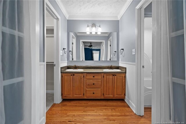 1608 Piney Creek Pl, Fayetteville, NC 28304 - bathroom with a textured ceiling, double vanity, wood finished floors, ornamental molding, and wainscoting