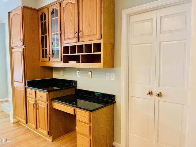 1512 Cumberland Rd, Chapel Hill, NC 27514 - kitchen featuring light wood-type flooring, glass insert cabinets, dark stone counters, and built in study area