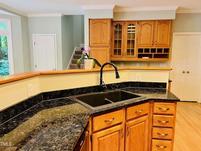 1512 Cumberland Rd, Chapel Hill, NC 27514 - kitchen featuring a sink, crown molding, brown cabinetry, light wood-type flooring, and glass insert cabinets