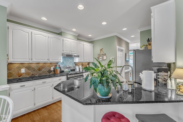 7613 Percy Ct, Raleigh, NC 27613 - kitchen featuring stainless steel range with gas cooktop, dark stone countertops, under cabinet range hood, a peninsula, and recessed lighting
