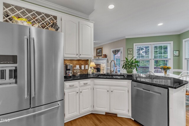 7613 Percy Ct, Raleigh, NC 27613 - kitchen featuring stainless steel appliances, a sink, a peninsula, crown molding, and white cabinets