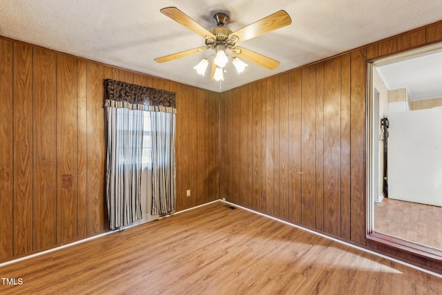 3115 Legion Rd, Hope Mills, NC 28348 - spare room with wood finished floors, ceiling fan, wood walls, and a textured ceiling