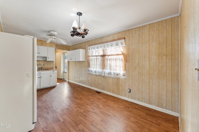 3115 Legion Rd, Hope Mills, NC 28348 - kitchen featuring freestanding refrigerator, white cabinets, a chandelier, wood finished floors, and wooden walls