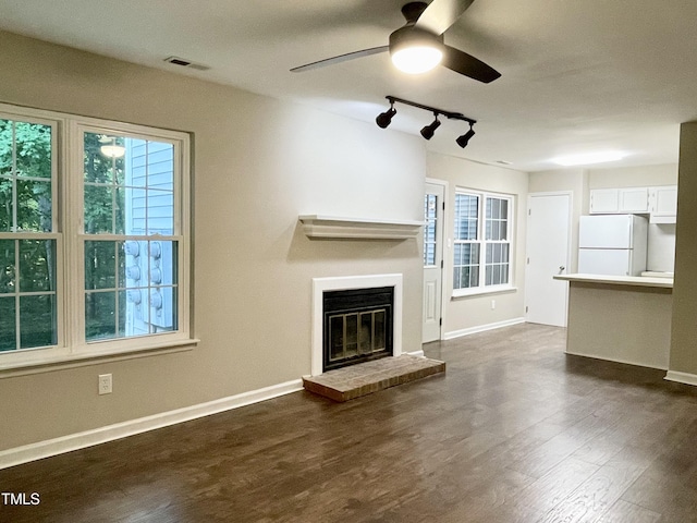 411 Gooseneck Dr Unit A1, Cary, NC 27513 - unfurnished living room featuring a ceiling fan, a fireplace, rail lighting, dark wood-style floors, and baseboards