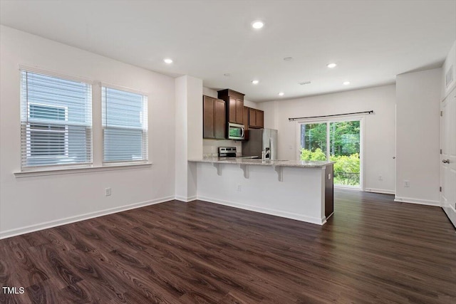 3064 Spline Cir, Raleigh, NC 27610 - kitchen with appliances with stainless steel finishes, dark wood-style flooring, a peninsula, a kitchen breakfast bar, and baseboards