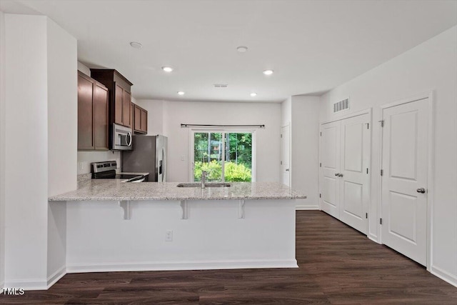 3064 Spline Cir, Raleigh, NC 27610 - kitchen featuring appliances with stainless steel finishes, a peninsula, recessed lighting, light stone countertops, and a kitchen bar