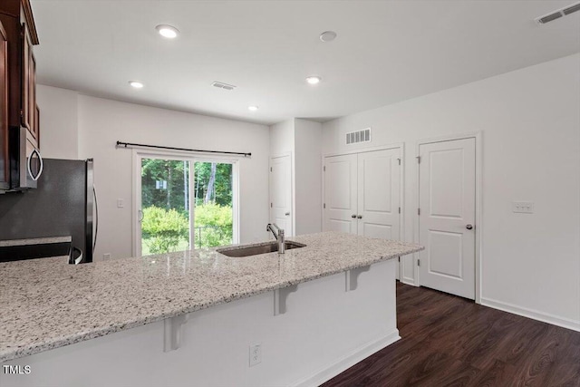 3064 Spline Cir, Raleigh, NC 27610 - kitchen featuring a sink, dark wood-style floors, appliances with stainless steel finishes, a breakfast bar area, and light stone countertops