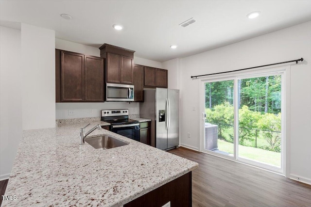 3064 Spline Cir, Raleigh, NC 27610 - kitchen featuring appliances with stainless steel finishes, a sink, dark brown cabinetry, light stone counters, and dark wood finished floors