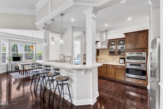 1808 Pennypacker Ln, Durham, NC 27703 - kitchen featuring stainless steel appliances, dark wood-style floors, wall chimney range hood, a breakfast bar, and light countertops
