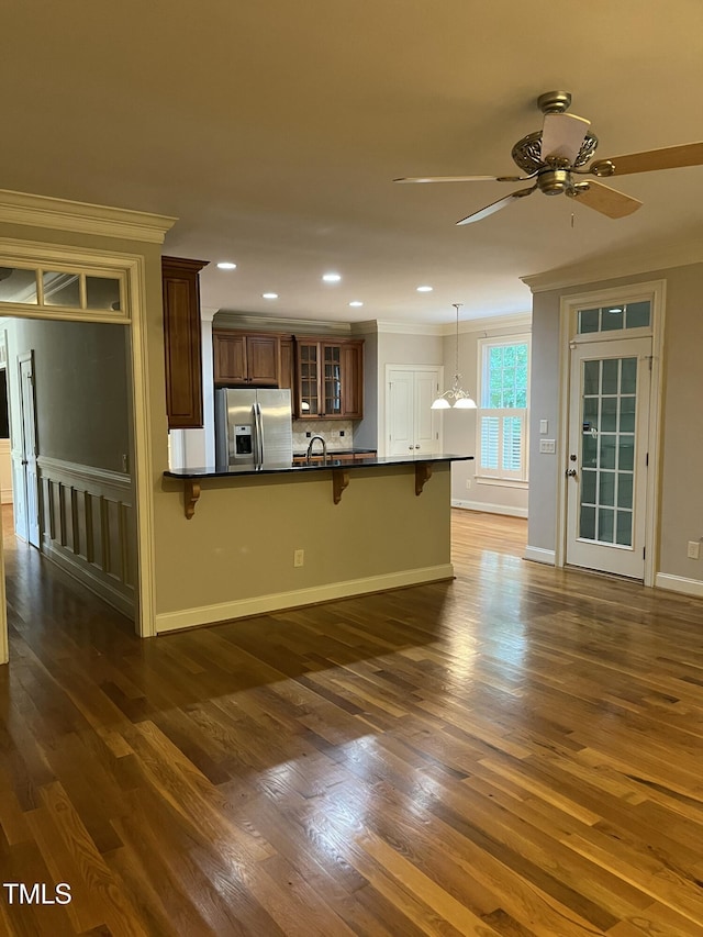 126 Riverglade Dr, Clayton, NC 27527 - kitchen with stainless steel refrigerator with ice dispenser, dark countertops, a breakfast bar, glass insert cabinets, and ornamental molding