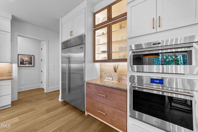 15517 Possum Track Rd, Raleigh, NC 27614 - kitchen with stainless steel appliances, light wood-type flooring, white cabinetry, glass insert cabinets, and baseboards