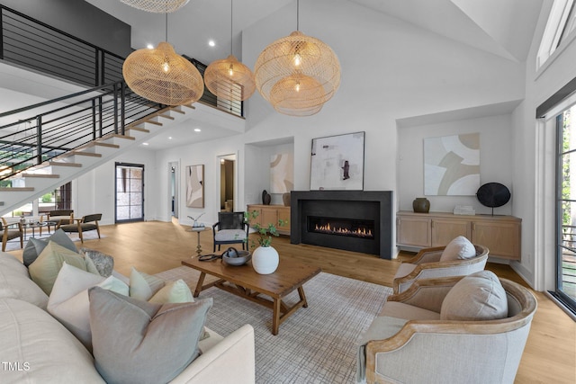 15517 Possum Track Rd, Raleigh, NC 27614 - living room with high vaulted ceiling, wood finished floors, stairs, a lit fireplace, and recessed lighting