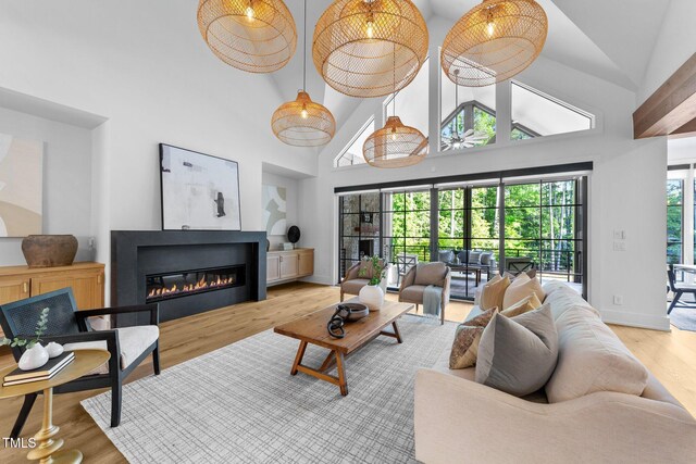 15517 Possum Track Rd, Raleigh, NC 27614 - living room with wood finished floors, high vaulted ceiling, a glass covered fireplace, and baseboards