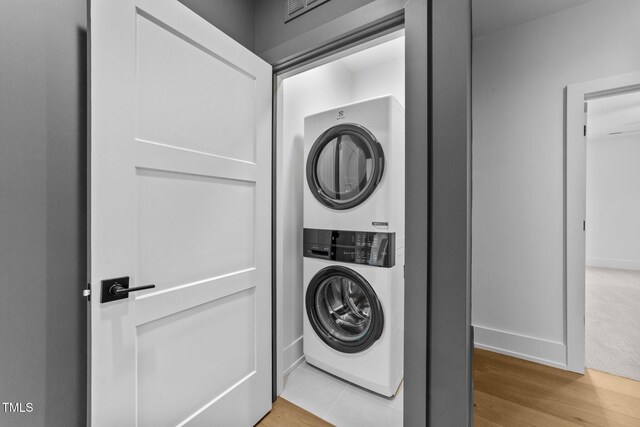 15517 Possum Track Rd, Raleigh, NC 27614 - laundry room with stacked washing machine and dryer, light wood-style flooring, and baseboards