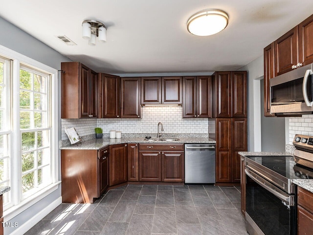 102 Sanair Ct, Apex, NC 27502 - kitchen with stainless steel appliances, a sink, tasteful backsplash, and light stone countertops