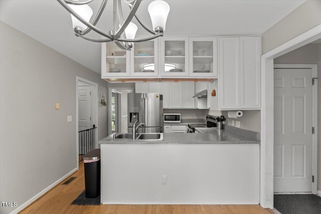 2750 Michelle Ct, Creedmoor, NC 27522 - kitchen with appliances with stainless steel finishes, under cabinet range hood, white cabinets, glass insert cabinets, and a chandelier