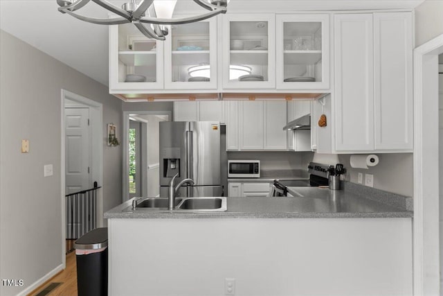 2750 Michelle Ct, Creedmoor, NC 27522 - kitchen featuring stainless steel appliances, under cabinet range hood, white cabinets, glass insert cabinets, and a chandelier