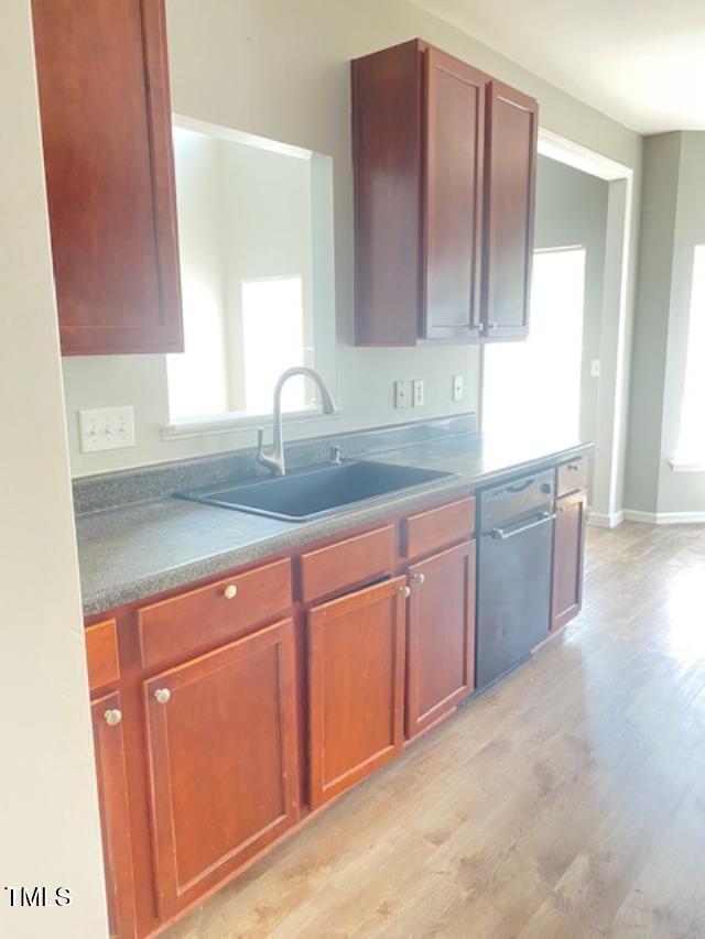 3207 Geary Trl, Raleigh, NC 27610 - kitchen with dishwasher, a sink, light wood-style flooring, and baseboards