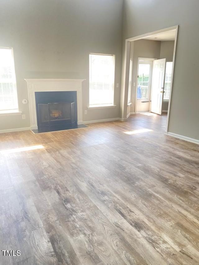 3207 Geary Trl, Raleigh, NC 27610 - unfurnished living room featuring wood finished floors, a fireplace with flush hearth, and baseboards