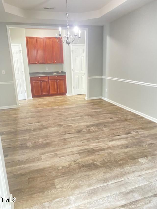 3207 Geary Trl, Raleigh, NC 27610 - unfurnished living room with a chandelier, baseboards, and light wood-style flooring