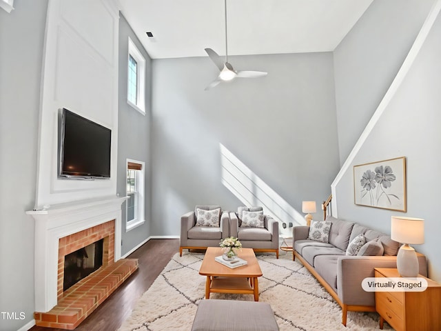 117 Brierridge Dr, Apex, NC 27502 - living area featuring a towering ceiling, a ceiling fan, wood finished floors, a brick fireplace, and baseboards