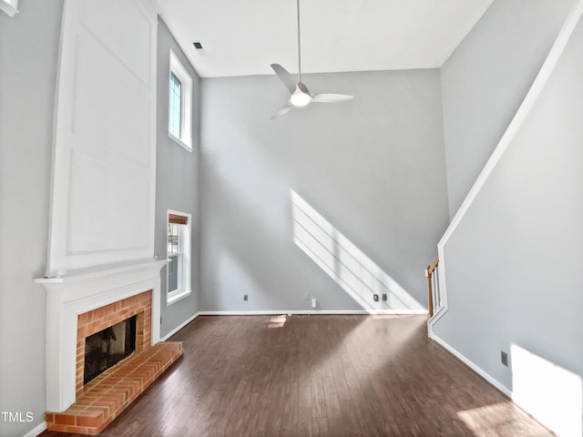 117 Brierridge Dr, Apex, NC 27502 - unfurnished living room featuring a towering ceiling, hardwood / wood-style flooring, a fireplace, a ceiling fan, and baseboards