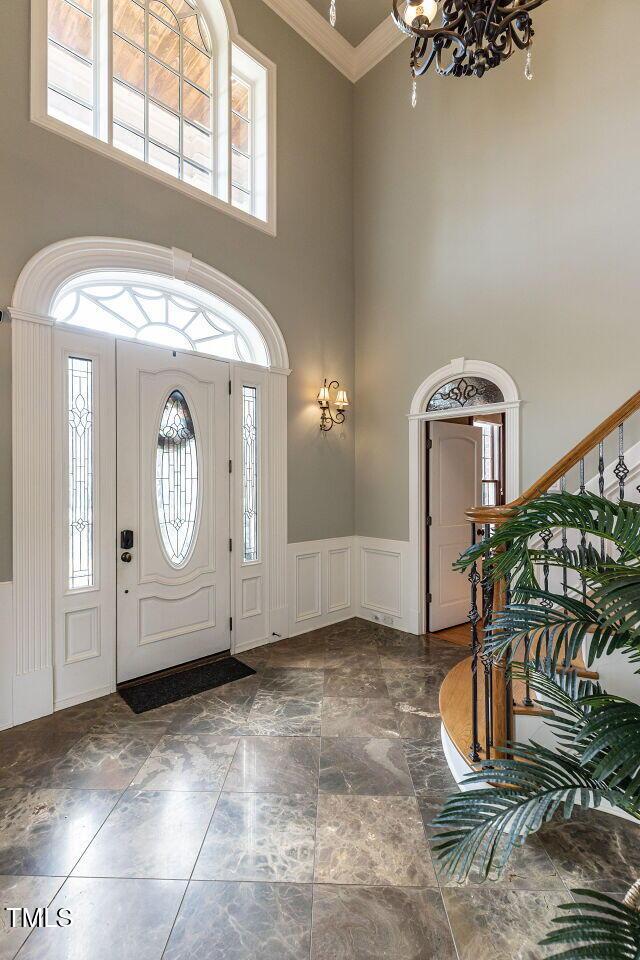 5768 Cavanaugh Dr, Raleigh, NC 27614 - entrance foyer featuring a towering ceiling, a decorative wall, healthy amount of natural light, a chandelier, and crown molding
