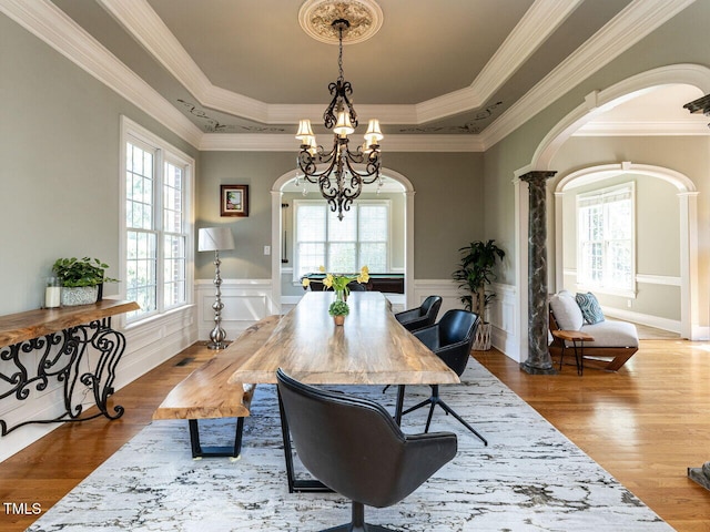 5768 Cavanaugh Dr, Raleigh, NC 27614 - dining space featuring arched walkways, a chandelier, a raised ceiling, wood finished floors, and crown molding