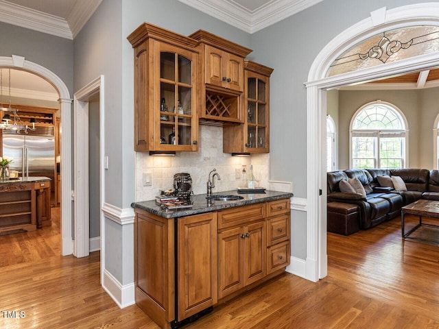 5768 Cavanaugh Dr, Raleigh, NC 27614 - indoor wet bar with light wood-style flooring, decorative backsplash, crown molding, stainless steel built in refrigerator, and arched walkways