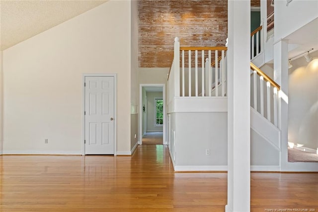 1718 Carthage St, Sanford, NC 27330 - unfurnished living room featuring wood finished floors, high vaulted ceiling, baseboards, and stairway
