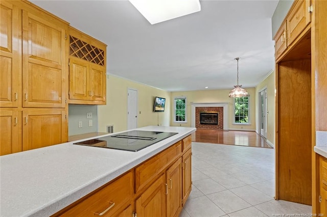 1718 Carthage St, Sanford, NC 27330 - kitchen featuring black electric cooktop, a brick fireplace, light countertops, light tile patterned flooring, and pendant lighting