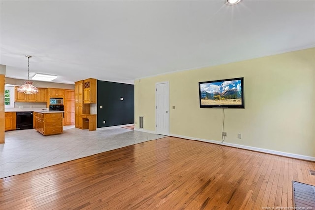 1718 Carthage St, Sanford, NC 27330 - unfurnished living room featuring light wood-style flooring, baseboards, and a chandelier