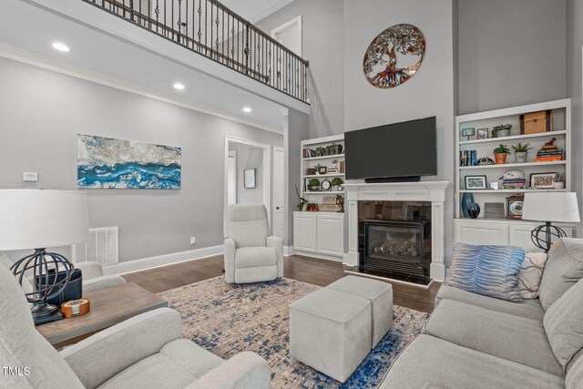 204 Franconia Way, Apex, NC 27502 - living room featuring crown molding, a towering ceiling, a tile fireplace, wood finished floors, and recessed lighting